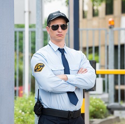 Охранник в синей рубашке с галстуком и кепке 